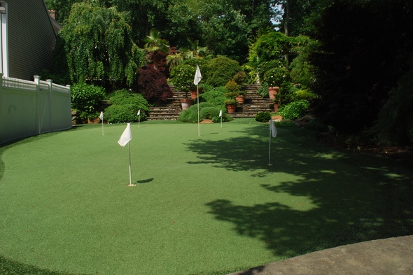 Charlotte Synthetic grass golf green with flags in a landscaped backyard