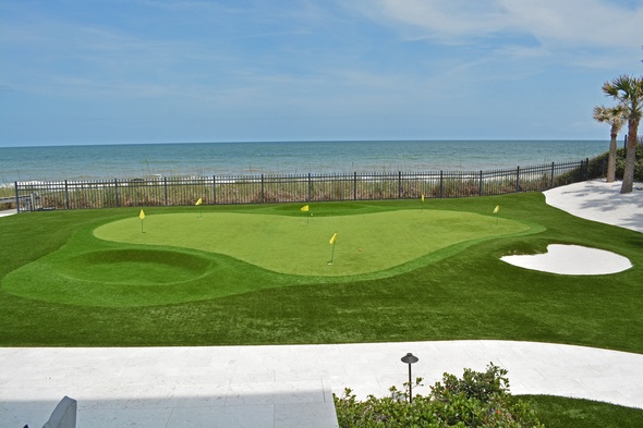 Charlotte Synthetic grass golf green by the sea with yellow flags and a sand bunker